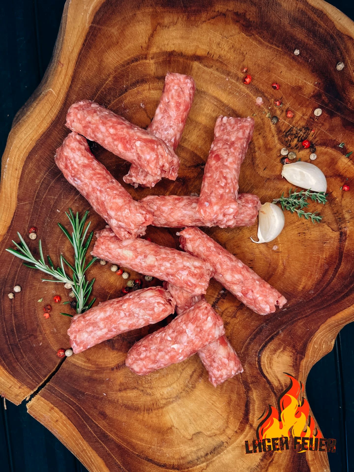 LF Ćevapi — frisch gerollt auf Holzbrett mit Rosmarin und Knoblauch