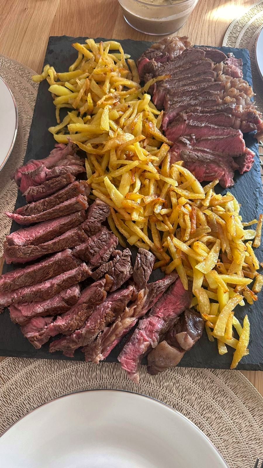 Aufgeschnittenes Steak mit Pommes auf Schieferplatte