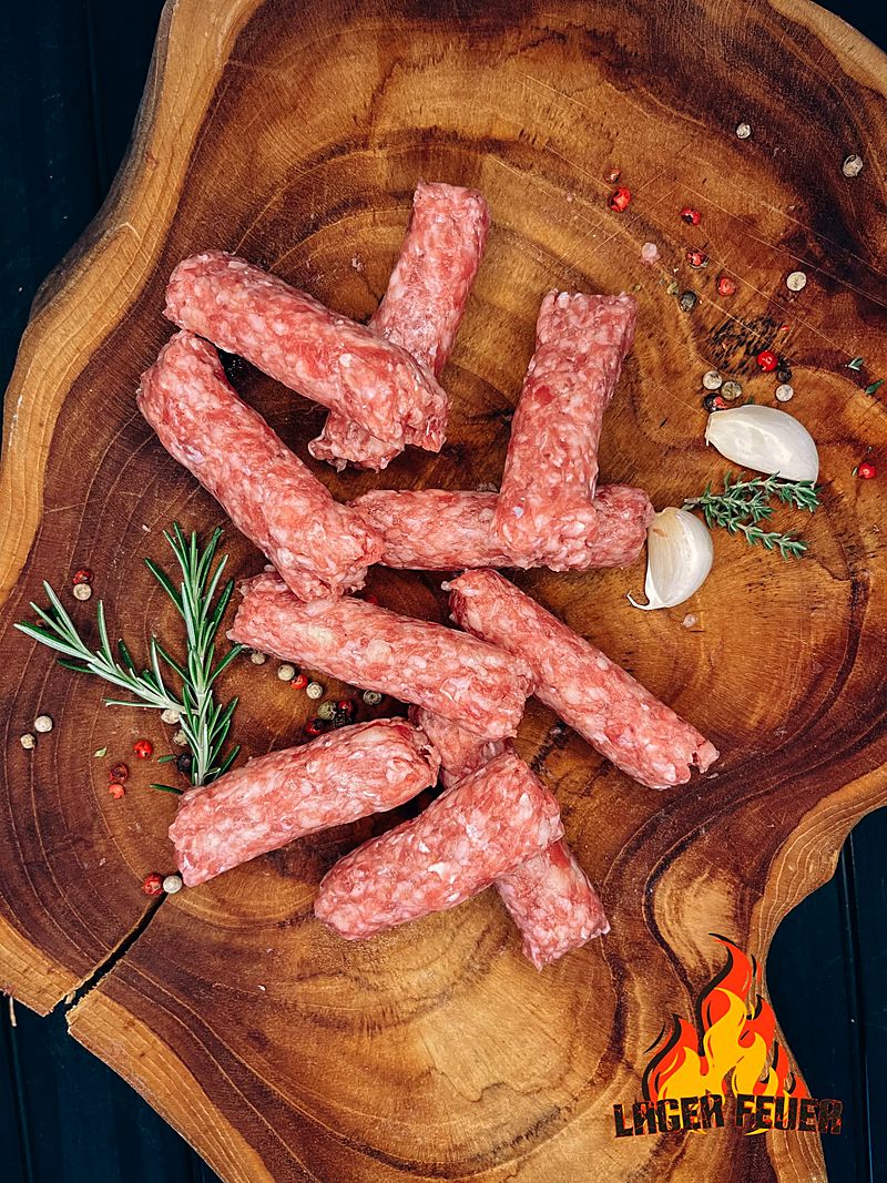 Ćevapi — frisch gerollt auf Holzbrett mit Rosmarin
